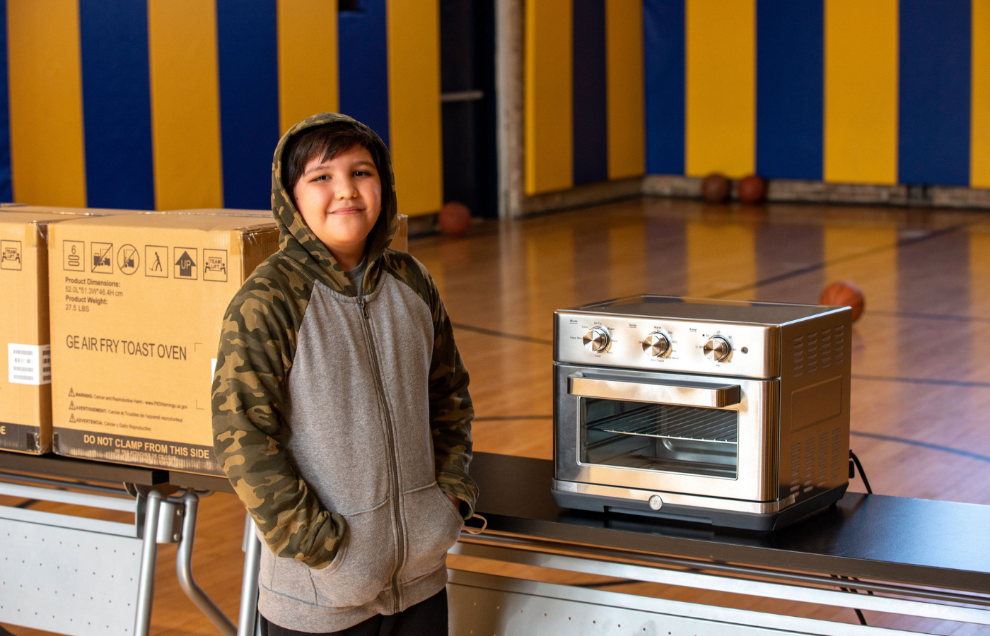 Young boy poses for a photo with his new toaster oven.