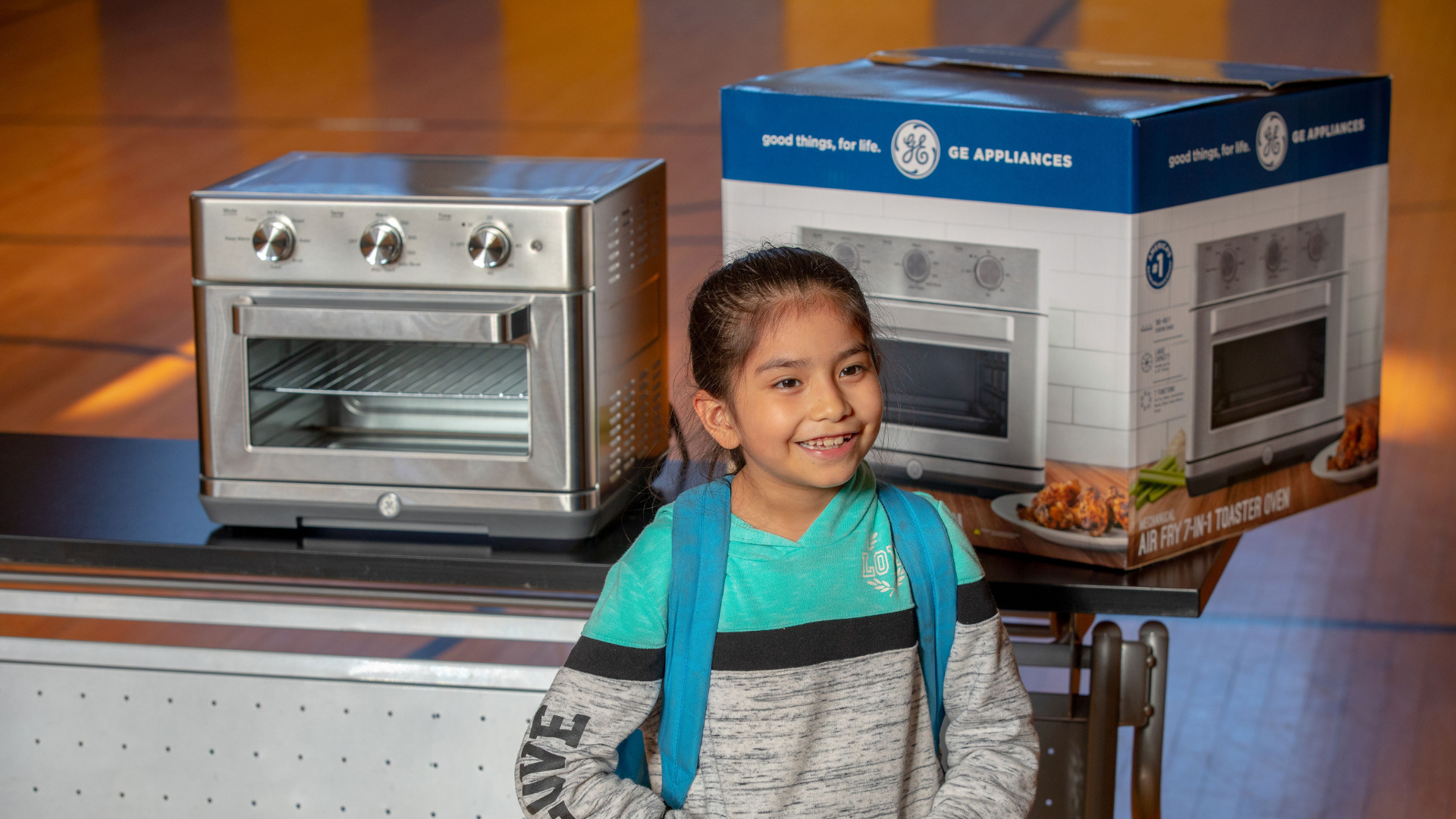 Young girl poses for photo in front of new toaster oven